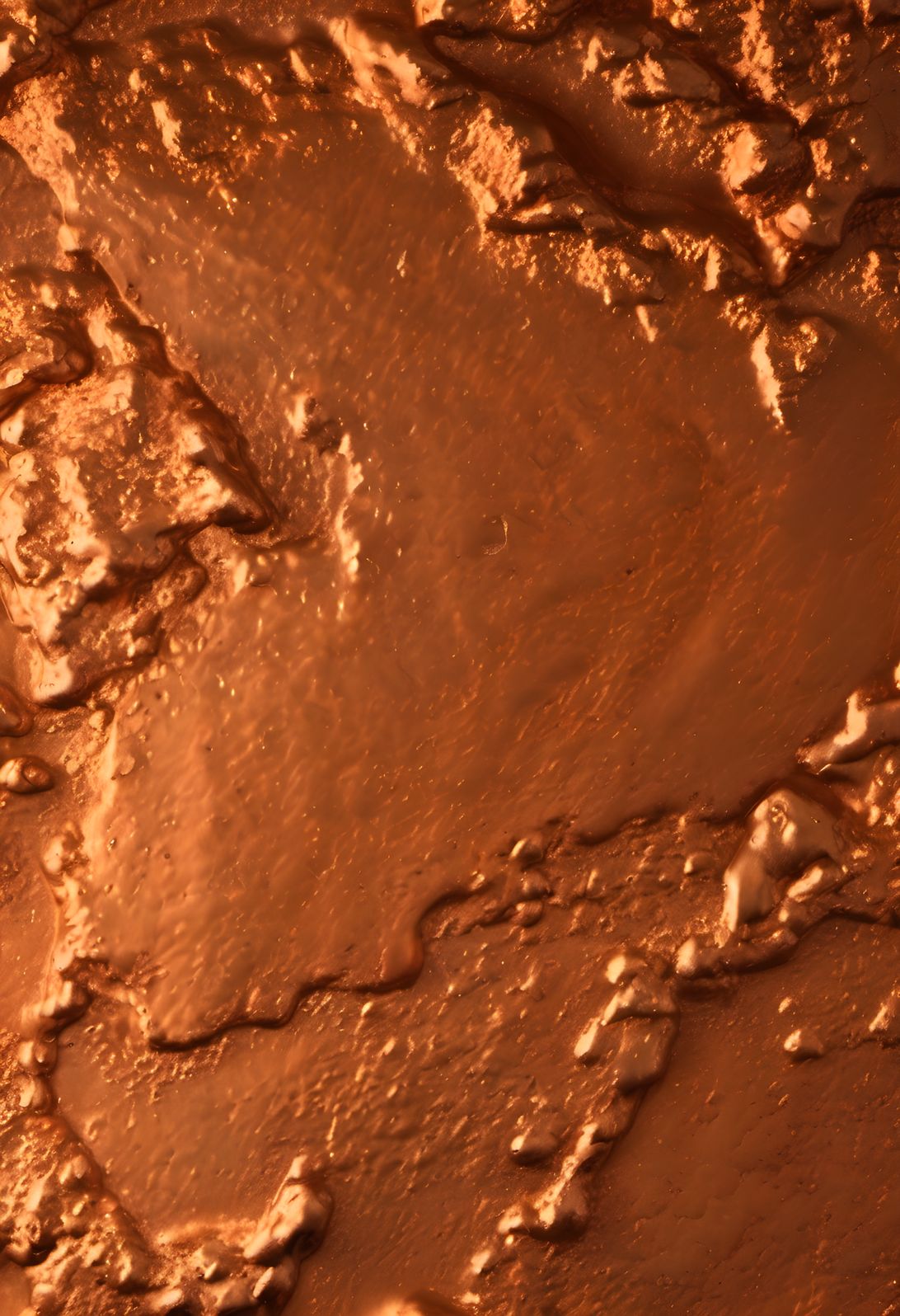 A molten metal surface glowing in orange in soft diffused light