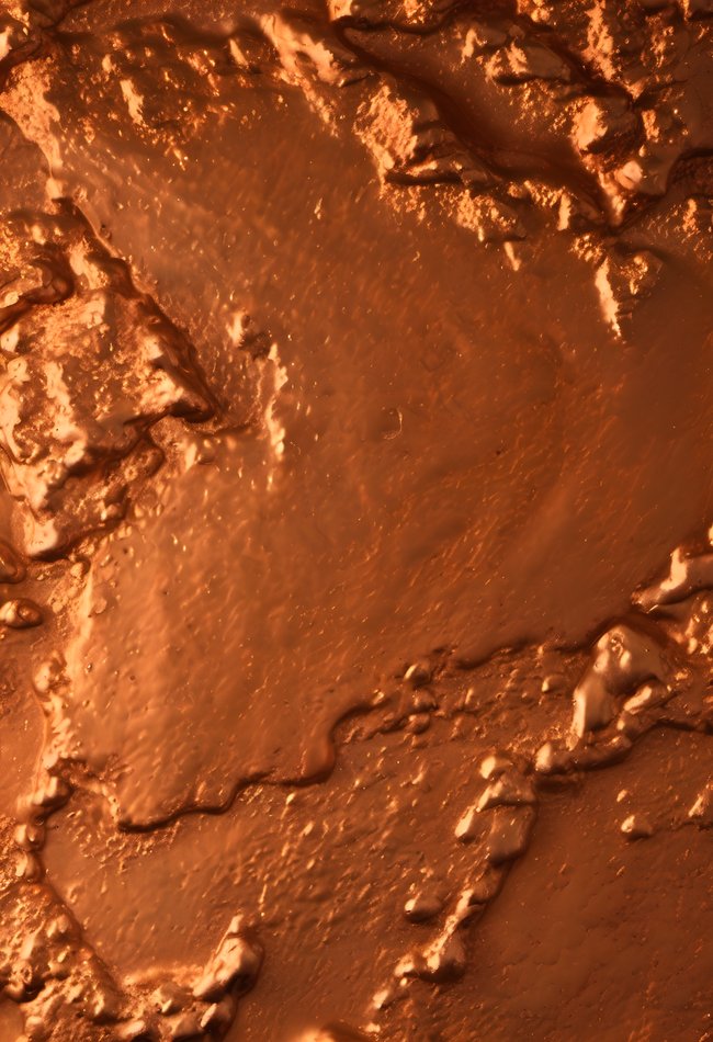 A molten metal surface glowing in orange in soft diffused light